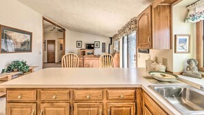 Una cocina con una isla grande, armarios de madera y una zona de comedor con sillas.