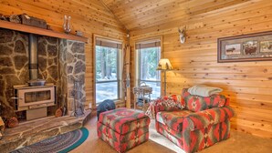 A cozy cabin interior with a stone fireplace, wooden walls, and a sofa with a patterned throw. - Cabin < 2 Mi to Tahoe Donner Downhill Ski Resort (Truckee)