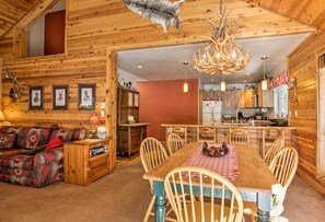 Relax in a spacious living area with a sofa and dining table for four, featuring a well-equipped kitchen and rustic charm.