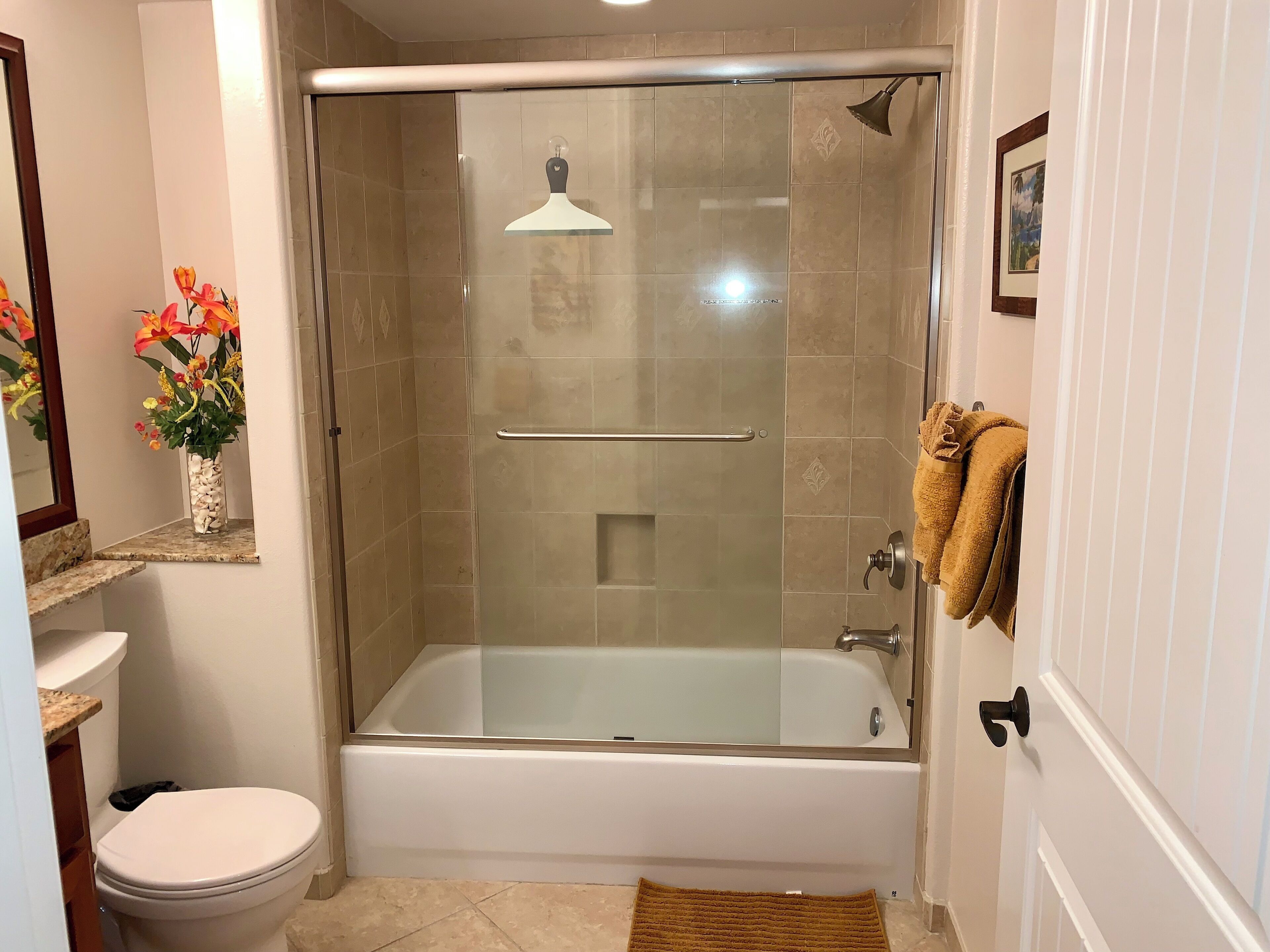 A bathroom with a glass-enclosed shower, a white bathtub, a toilet, and a sink.