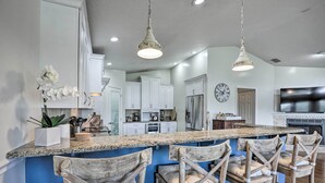A kitchen with white cabinets, a granite countertop, and wooden bar stools. - St Augustine Home w/ Swim Spa & Marsh Views! (St. Augustine)
