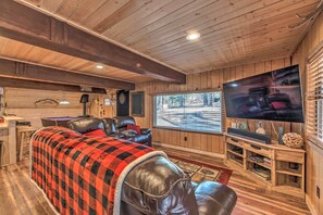 A cozy living room with a large TV, wooden walls, a leather couch, and a fireplace. - Ruidoso A-frame Cabin ~ 1 Mi to Grindstone Lake! (Ruidoso)