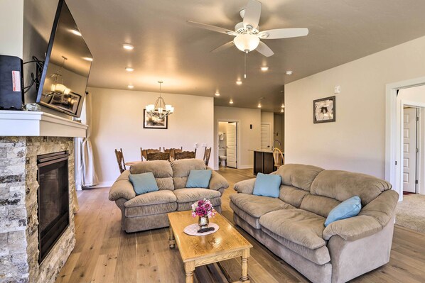 A living room with two beige sofas, a wooden coffee table, a fireplace, and a ceiling fan.