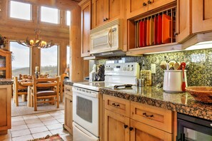 Une cuisine avec des armoires en bois, un plan de travail en granit, une cuisinière et un four à micro-ondes.