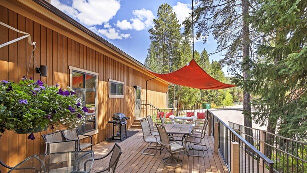 A wooden deck with outdoor furniture, a barbecue grill, and hanging flower baskets. - Winter Park Condo w/ Hot Tubs, 4 Mi to Ski Resort! (Winter Park)