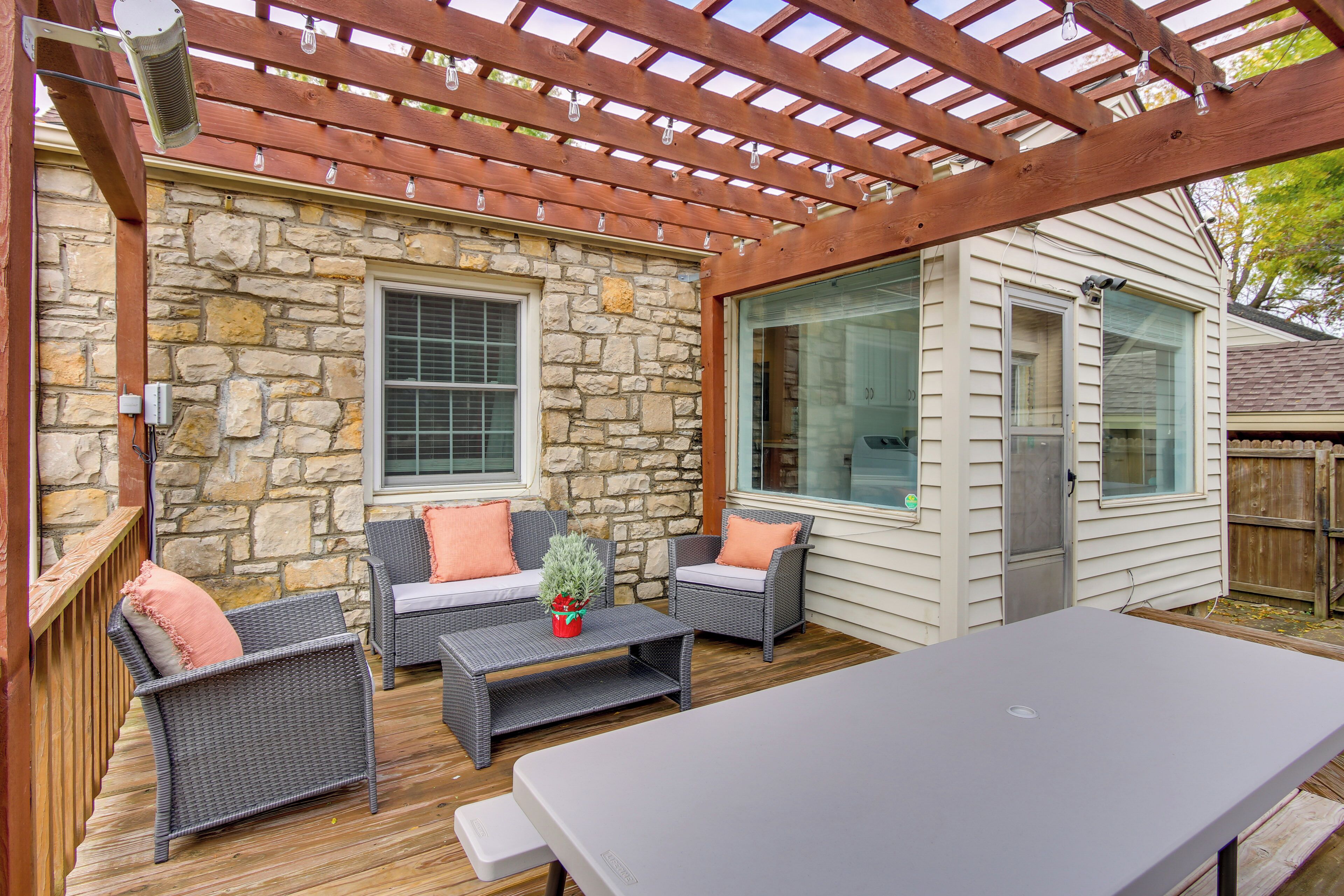 A covered patio with wicker furniture, a stone wall, and a wooden pergola.
