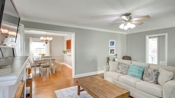 A living room with a sofa, coffee table, and a dining area with chairs and a table.