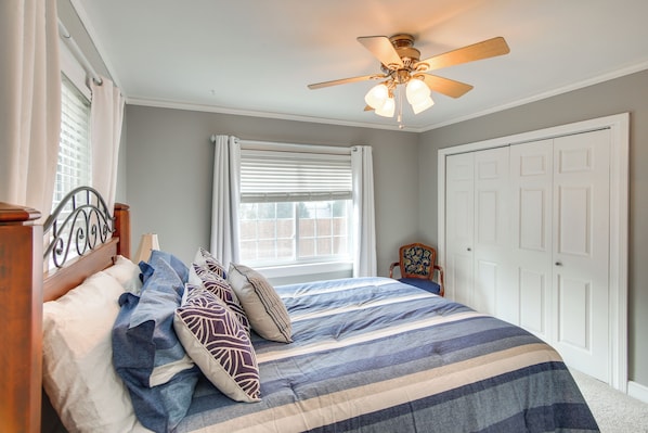 Un dormitorio con cama, ventilador de techo, ventana con persianas y puerta.
