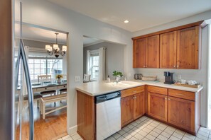 Cocina moderna con armarios de madera, lavavajillas y cafetera.