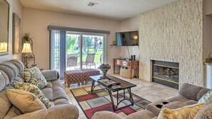Ein Wohnzimmer mit Sofa, Couchtisch, Kamin und einem an der Wand befestigten Fernseher.
