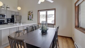 A modern kitchen with a large island, white cabinets, and a dining area with a long table and chairs. - Balcony & Ski Slope Views: Idyllic Granby Condo! (Granby)