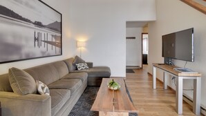 A modern living room with a sofa, coffee table, and a flat-screen TV. - Balcony & Ski Slope Views: Idyllic Granby Condo! (Granby)