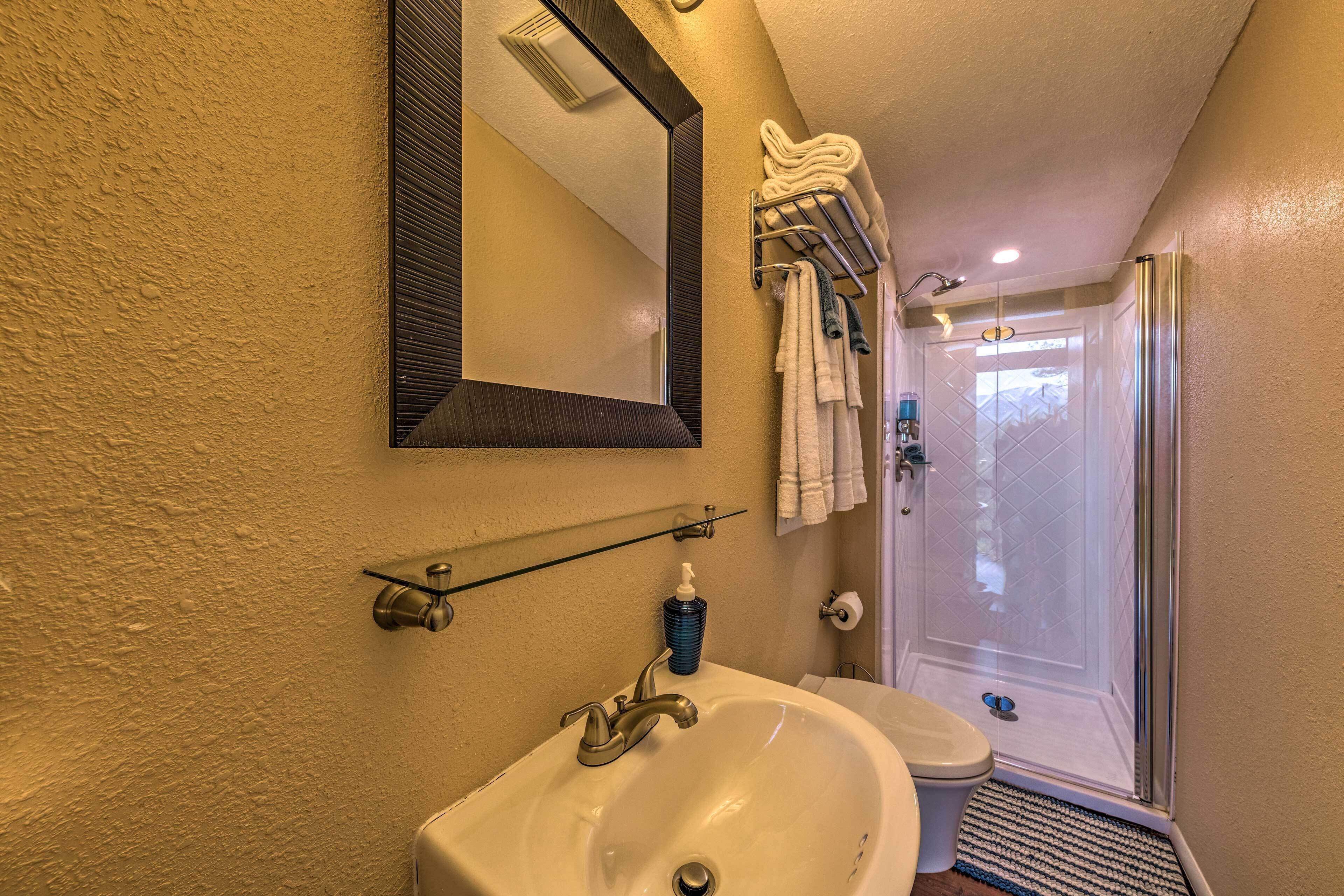 A bathroom with a white sink, a mirror, a towel rack, and a shower area.