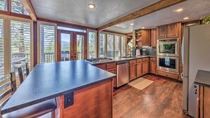 A spacious kitchen with wooden cabinets, a large island, and a view of the outdoors. - Hot Tub, Game Room & Sauna: Ruidoso Hideaway! (Ruidoso)