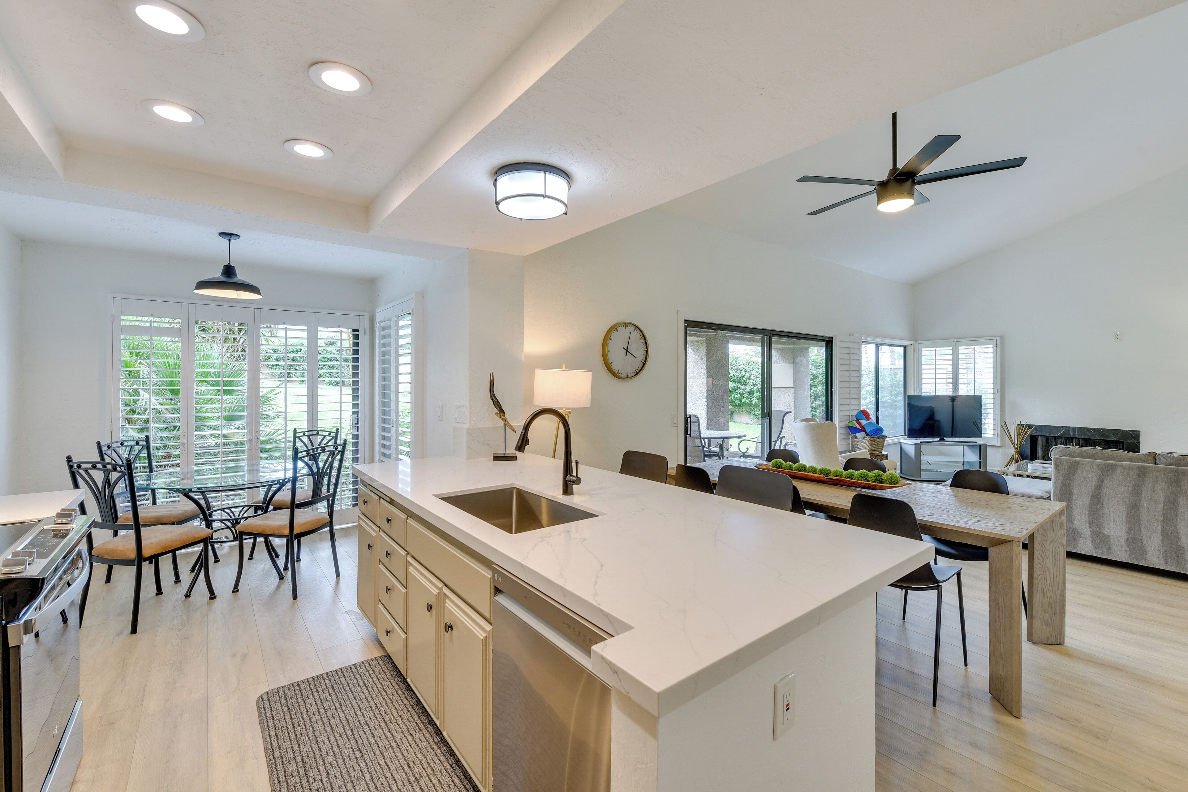 A spacious kitchen with a central island, a dining area with chairs, and a living room with a sofa.