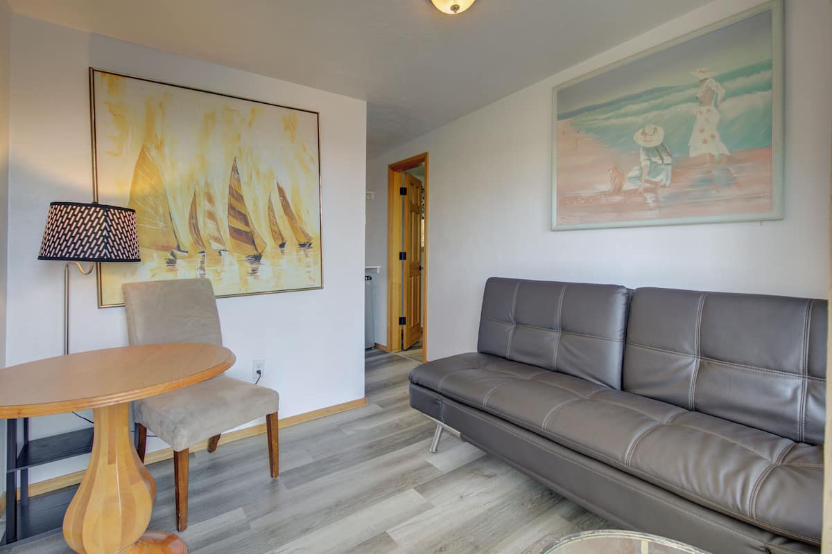 A living room with a sofa, a chair, a table, and two paintings.
