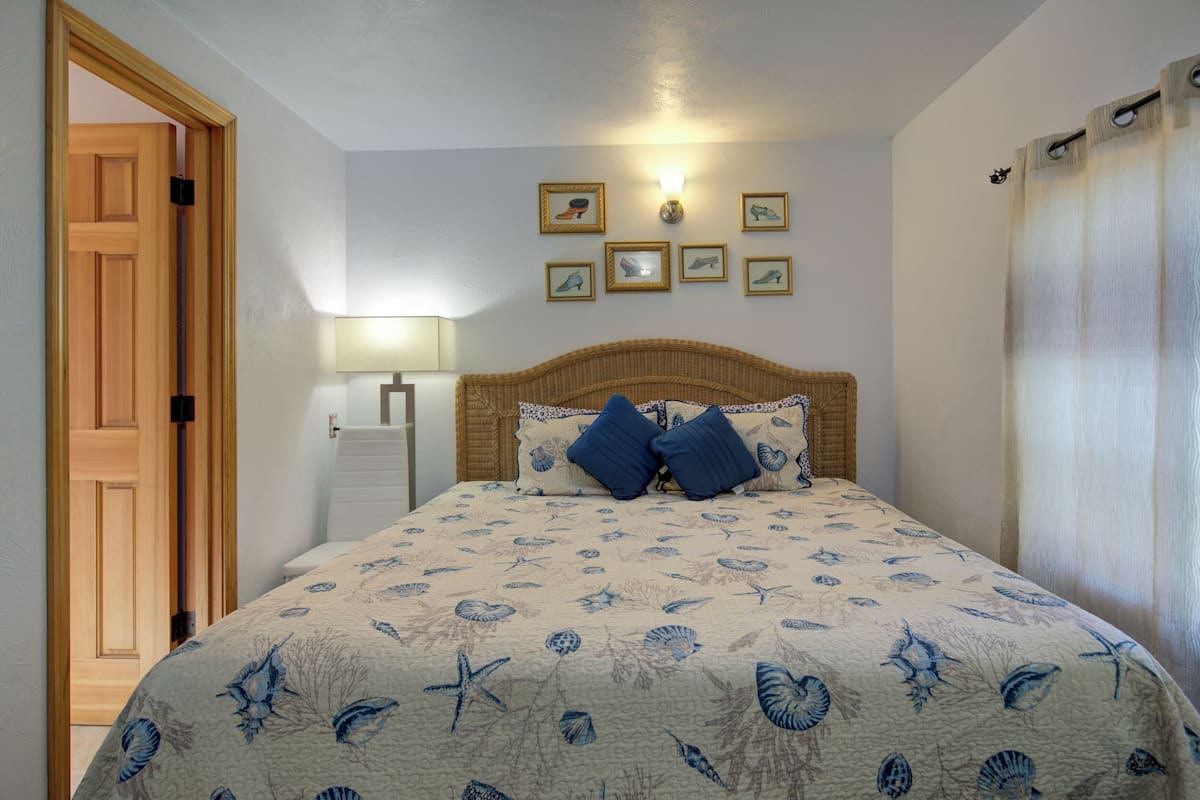 A bedroom with a bed, a nightstand, a lamp, and framed pictures on the wall.
