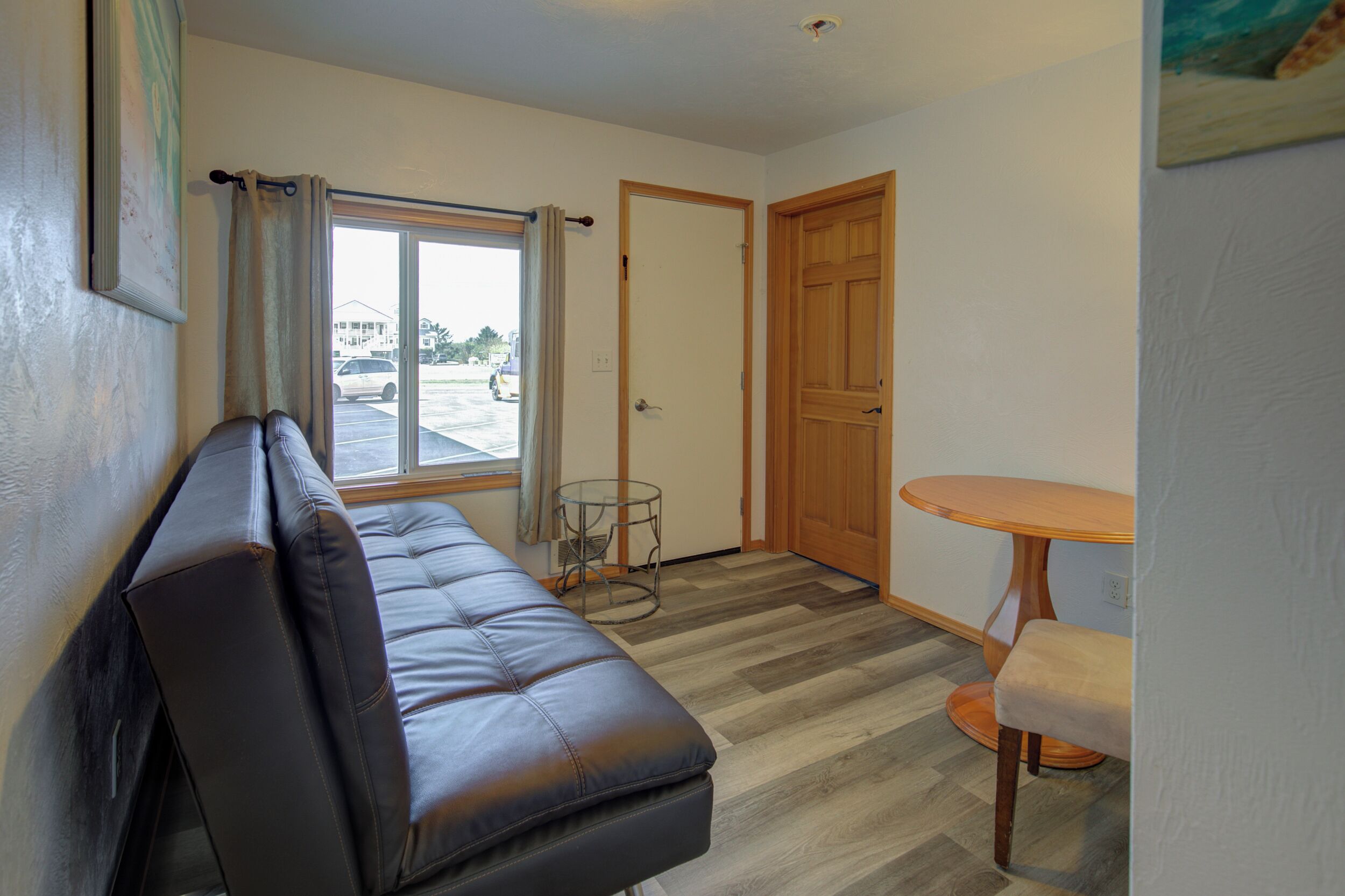 A room with a leather sofa, a small round table, and a door leading to another room.