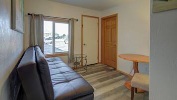 A room with a leather sofa, a small round table, and a door leading to another room.