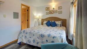 A bedroom with a bed, a wooden door, a wall-mounted lamp, and framed pictures. - The Westerly Motel (Ocean Shores)
