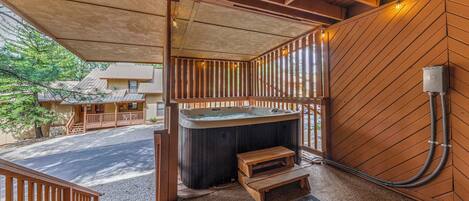 Een hottub met houten treden, een houten terras en uitzicht op de straat.