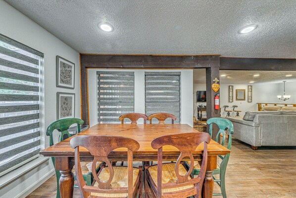 A dining area with a wooden table and chairs, a kitchen in the background, and a gray sofa. - Spacious Ruidoso Retreat w/ Hot Tub & 2 Kitchens! (Ruidoso)