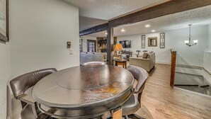 A dining area with a round table and chairs, a sofa, and a television in the background. - Spacious Ruidoso Retreat w/ Hot Tub & 2 Kitchens! (Ruidoso)