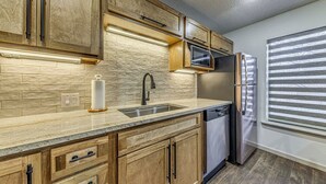 A kitchen with wooden cabinets, a stainless steel sink, a microwave, and a refrigerator. - Spacious Ruidoso Retreat w/ Hot Tub & 2 Kitchens! (Ruidoso)