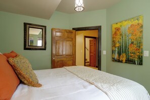 A bedroom with a bed, pillows, a wooden door, and a painting on the wall. - Hot Tub & Mtn Views Pristine Breckenridge Home! (Breckenridge)
