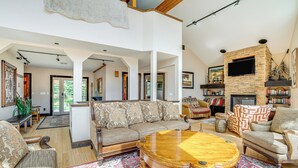 Ein großzügiges Wohnzimmer mit einem großen Couchtisch aus Holz, einem beigen Sofa und einem Kamin.