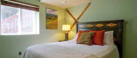 A bedroom with a bed, a nightstand, a lamp, and a painting on the wall.