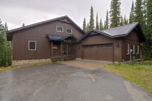 A two-story wooden building with a garage, a front porch, and a driveway.