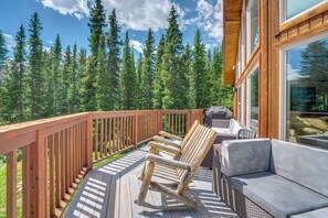A wooden deck with outdoor furniture, including chairs and a sofa, overlooking a forested area. - Hot Tub & Mtn Views Pristine Breckenridge Home! (Breckenridge)