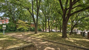 A park with trees, a brick wall, and a pathway. - Midtown Baltimore Hub Half Mi to Penn Station (Baltimore)