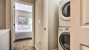 A laundry room with a washing machine and dryer, a door leading to a bedroom with a bed and a painting on the wall. - Midtown Baltimore Hub Half Mi to Penn Station (Baltimore)