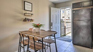 A kitchen with a wooden table, chairs, a refrigerator, and a door leading outside. - Midtown Baltimore Hub Half Mi to Penn Station (Baltimore)