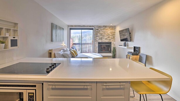 Una cocina moderna con una isla central, un revestimiento de piedra en la pared y vistas a un balcón.