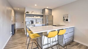 Una cocina moderna con una isla central, taburetes de bar y electrodomésticos integrados.