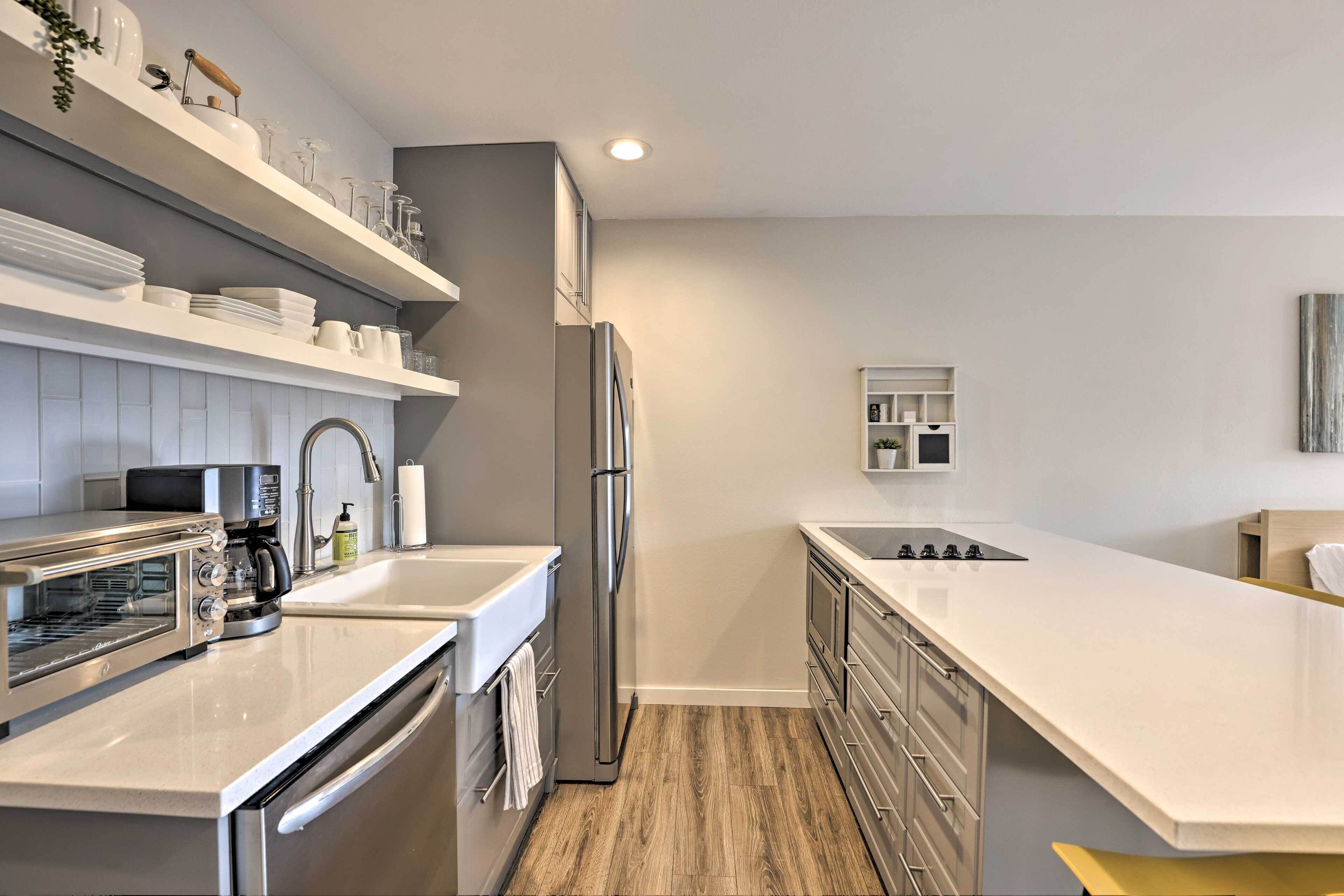 A modern kitchen with stainless steel appliances, white cabinetry, and a wooden floor.