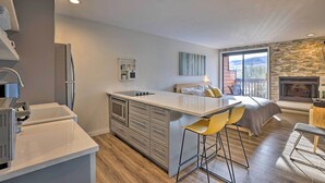 Una cocina moderna con una isla central, taburetes de bar, una chimenea y un amplio ventanal con vistas.
