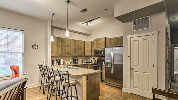 Una cocina moderna con armarios de madera, electrodomésticos de acero inoxidable y una isla central con taburetes de bar.