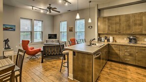 Una cocina moderna con una isla central, suelo de madera y una zona de comedor con sillas rojas.