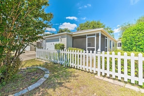 A mobile home with a screened porch, a white picket fence, and a well-maintained lawn.