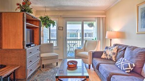 A living room with a sofa, armchairs, a coffee table, a TV stand, and a balcony with a view. - Walk to Beach! Isle of Palms Condo w/ Pool Access (Isle of Palms)