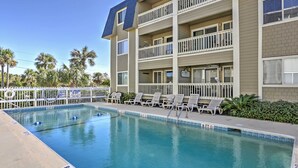 A pool area with lounge chairs, a lifeguard sign, and a multi-story building with balconies. - Walk to Beach! Isle of Palms Condo w/ Pool Access (Isle of Palms)