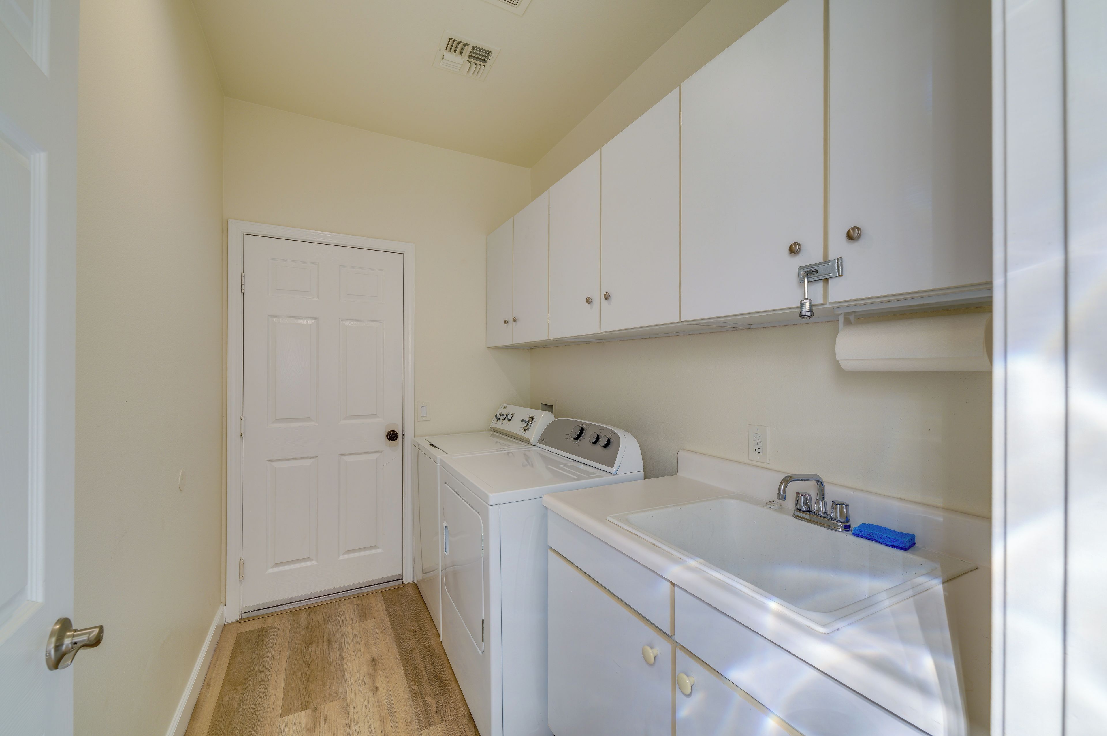 A laundry room with a washer and dryer, a sink, and a door.