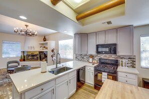 A modern kitchen with a central island, stainless steel appliances, and a chandelier. - Bermuda Dunes Home w/ Private Pool, Patio & Grill! (Indio)