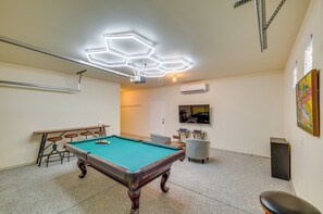 A pool table with a hexagonal ceiling light fixture, a television mounted on the wall, and a painting on the wall. - Bermuda Dunes Home w/ Private Pool, Patio & Grill! (Indio)