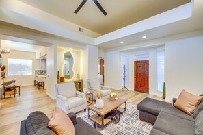 A spacious living room with a large sofa set, a coffee table, and a dining area with a kitchen in the background. - Bermuda Dunes Home w/ Private Pool, Patio & Grill! (Indio)