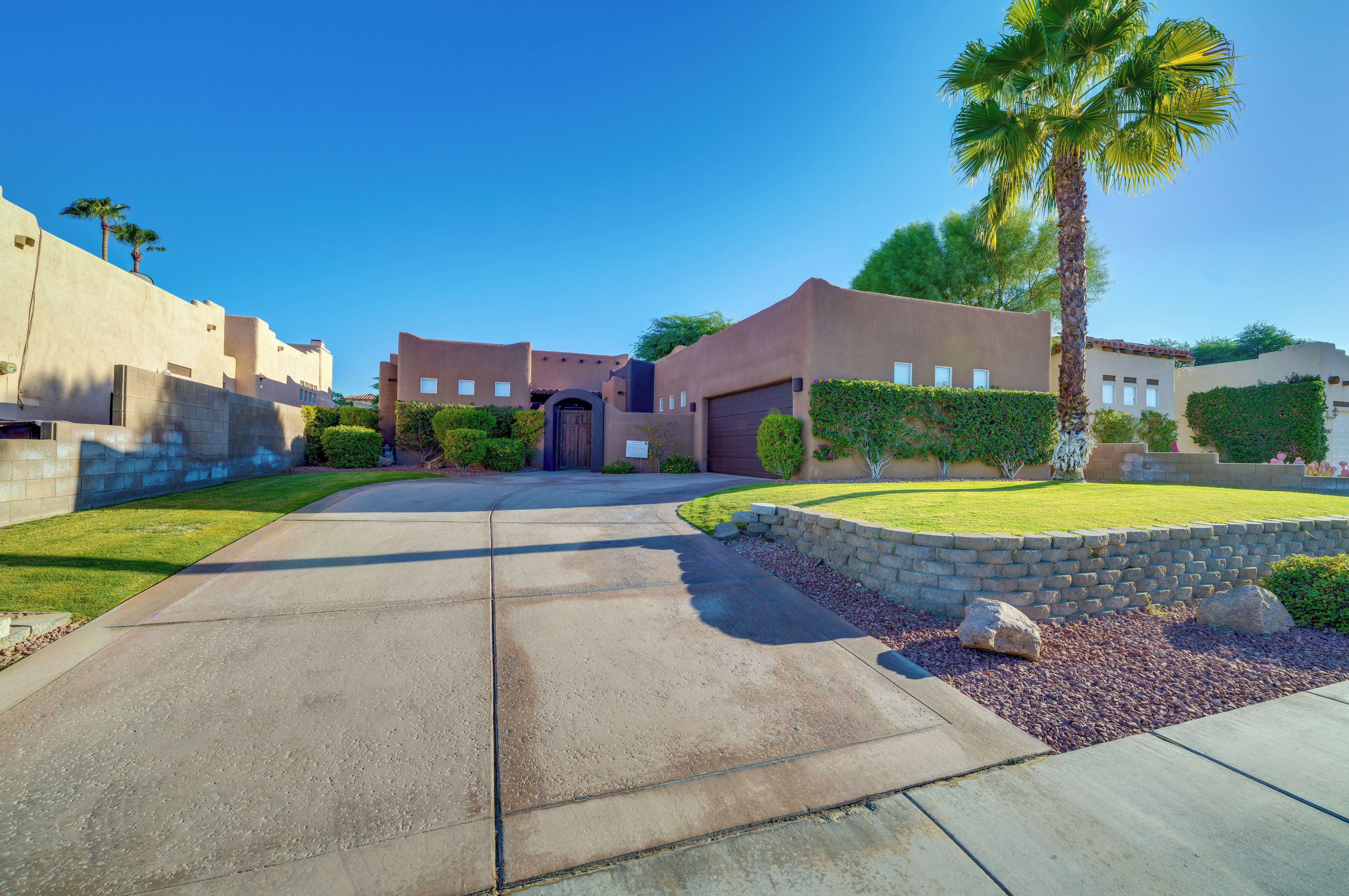 A residential area with a paved driveway leading to a house with a dark brown door and a small porch.